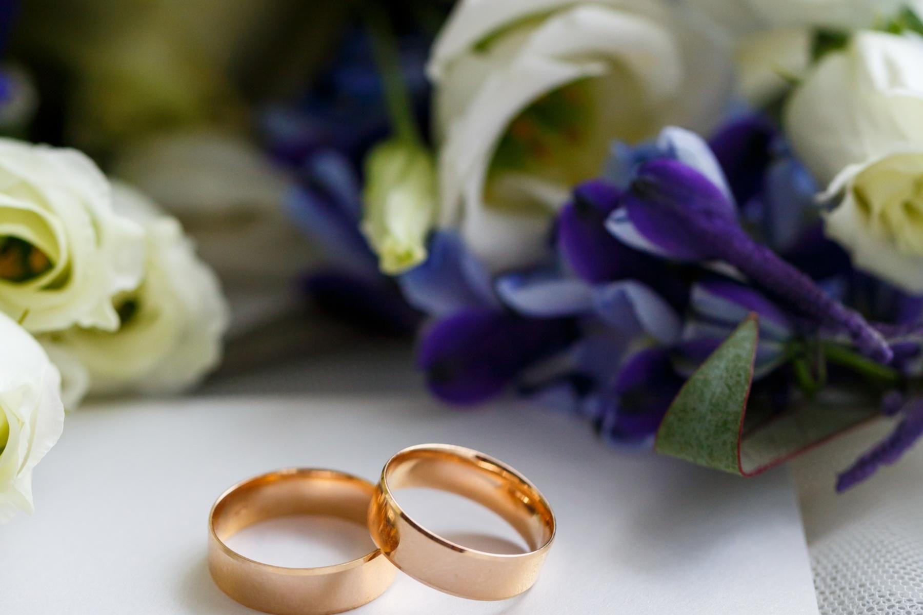 Zwei Eheringe liegen vor einem Blumenstrauß