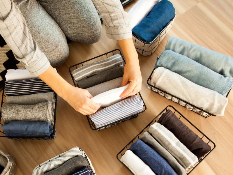 Kleidungsstücke werden nach einem bestimmten System gerollt/gefaltet und unter anderem nach Farben in verschiedene Körben einsortiert.